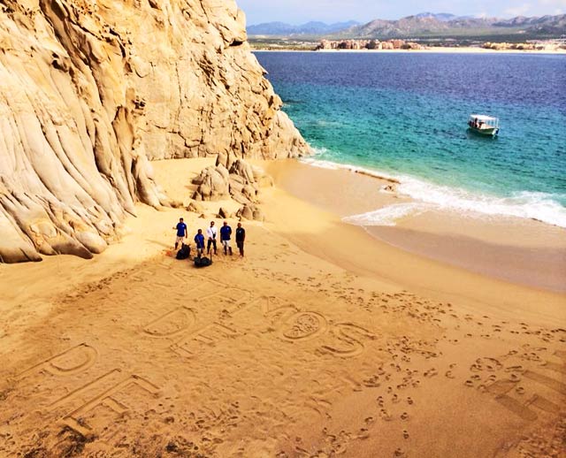 The Cabo Expeditions Team providing post-storm beach cleanup. "Estamos de Pie" translates to "We are Standing!"